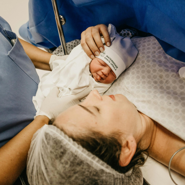 A mother cradling her newborn immediately after childbirth in a hospital setting.
